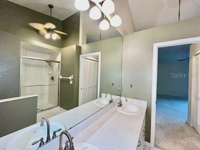 bathroom featuring vaulted ceiling, ceiling fan, walk in shower, and vanity