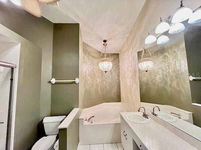 bathroom featuring a bathtub, vanity, toilet, and tile patterned flooring