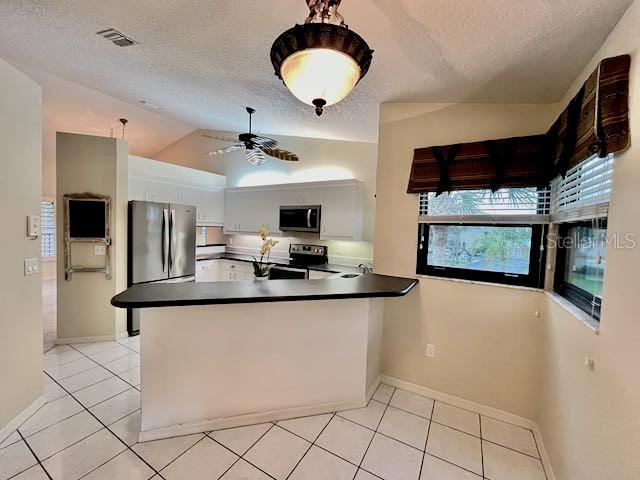 kitchen featuring white cabinetry, kitchen peninsula, ceiling fan, stainless steel appliances, and lofted ceiling