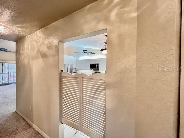 interior details with a textured ceiling, ceiling fan, and carpet