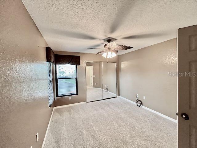 unfurnished room featuring ceiling fan, carpet, and a textured ceiling