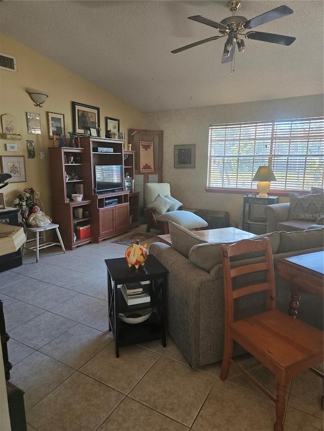 living room featuring vaulted ceiling, ceiling fan, light tile patterned floors, and a textured ceiling