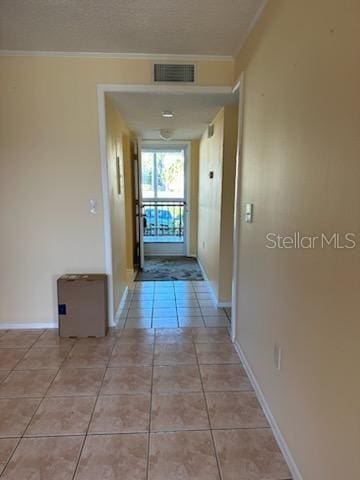 corridor with crown molding and light tile patterned flooring