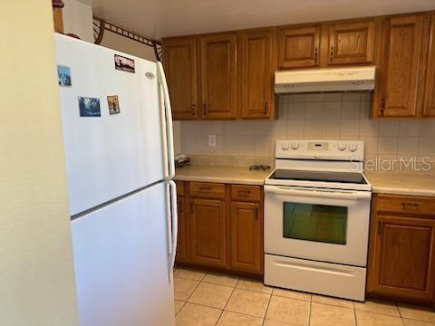 kitchen with backsplash, white appliances, and light tile patterned floors