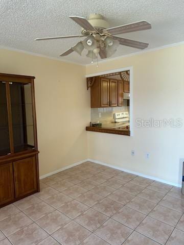 spare room featuring ceiling fan, light tile patterned flooring, crown molding, and a textured ceiling