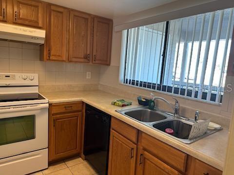 kitchen featuring dishwasher, decorative backsplash, electric range, sink, and light tile patterned flooring