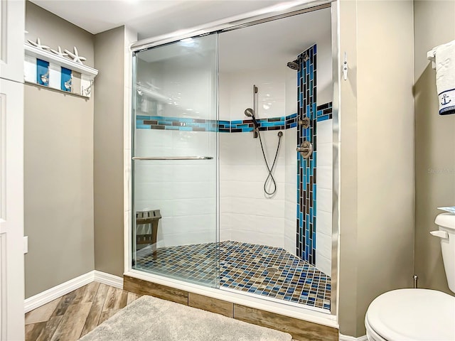 bathroom featuring a shower with shower door and toilet