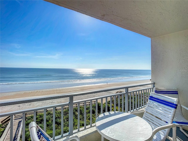 balcony featuring a beach view and a water view