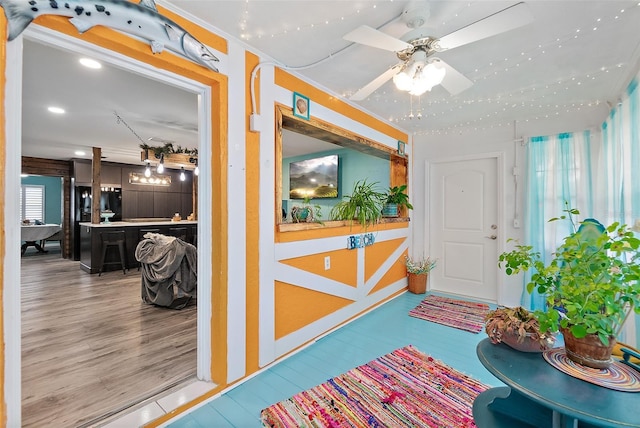 interior space featuring wood-type flooring, ceiling fan, and ornamental molding