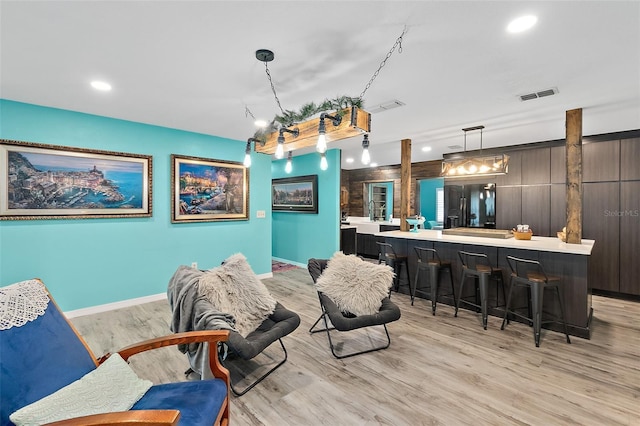 interior space with dark brown cabinets, light wood-type flooring, pendant lighting, and black fridge with ice dispenser