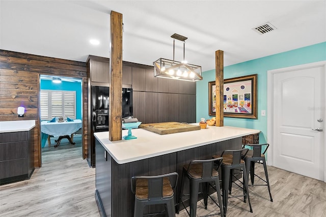 kitchen with a kitchen breakfast bar, pendant lighting, a center island, and dark brown cabinetry