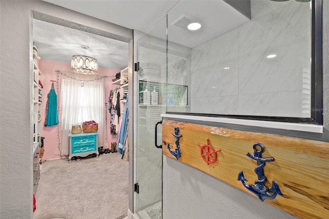 bathroom with a shower with shower door, a textured ceiling, and an inviting chandelier