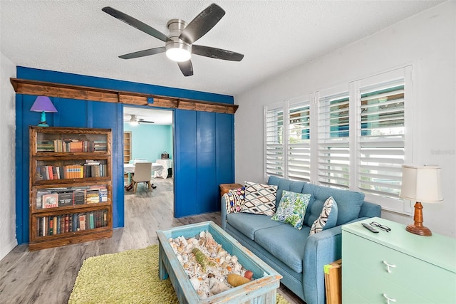 living area featuring ceiling fan, a textured ceiling, and light wood-type flooring