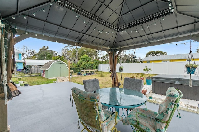 view of patio / terrace featuring a storage unit, a gazebo, and a hot tub