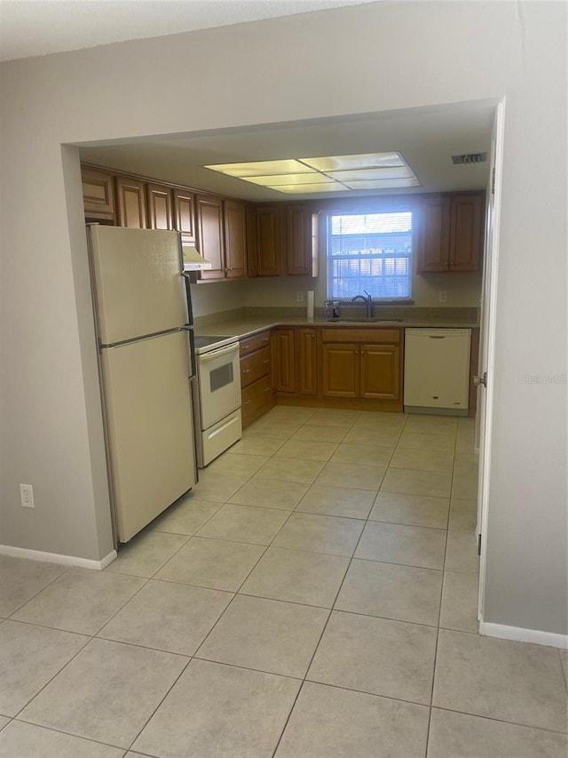 kitchen with sink, white appliances, and light tile patterned flooring