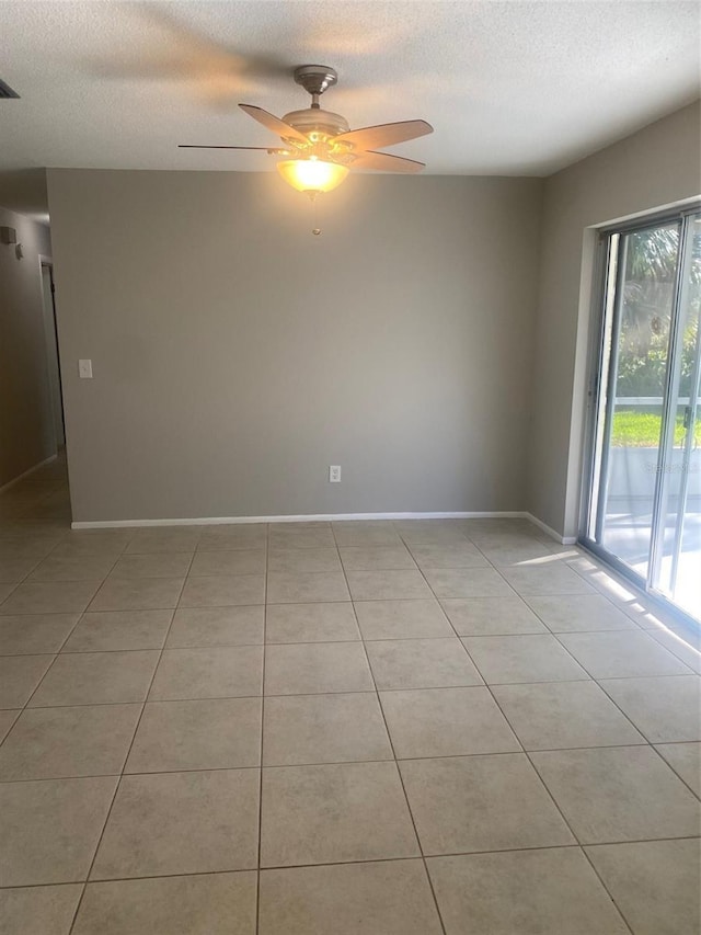 spare room with ceiling fan, light tile patterned floors, and a textured ceiling