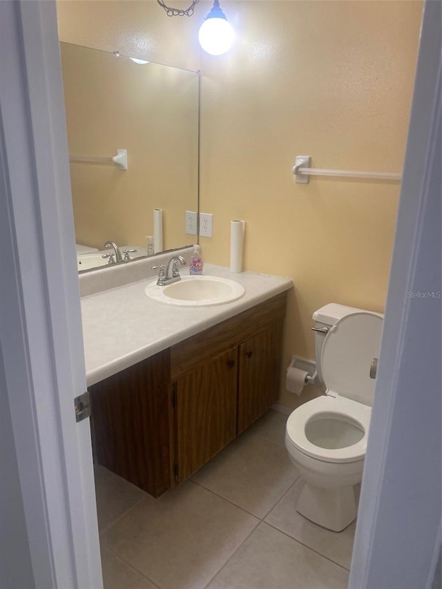 bathroom with toilet, vanity, and tile patterned flooring