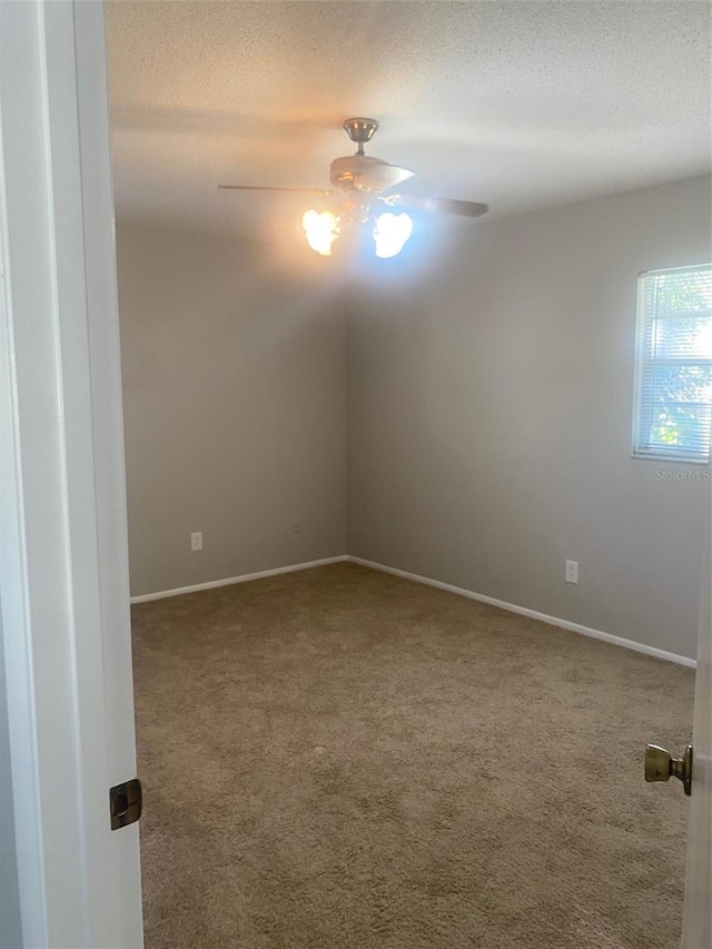 empty room featuring ceiling fan, a textured ceiling, and carpet flooring