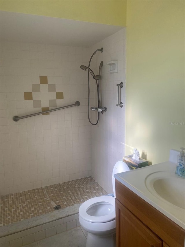 bathroom featuring toilet, tile patterned flooring, a tile shower, and vanity