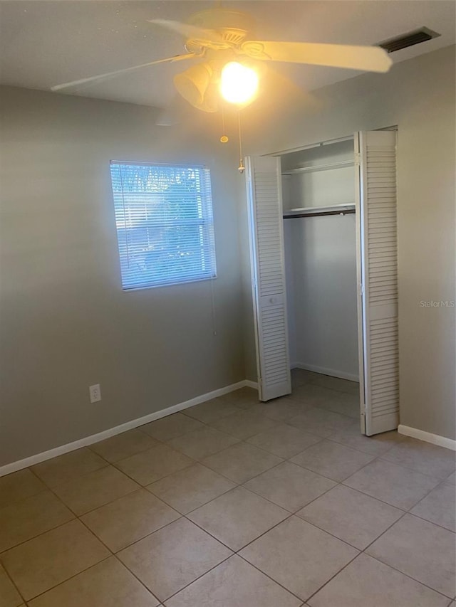 unfurnished bedroom featuring ceiling fan, light tile patterned flooring, and a closet