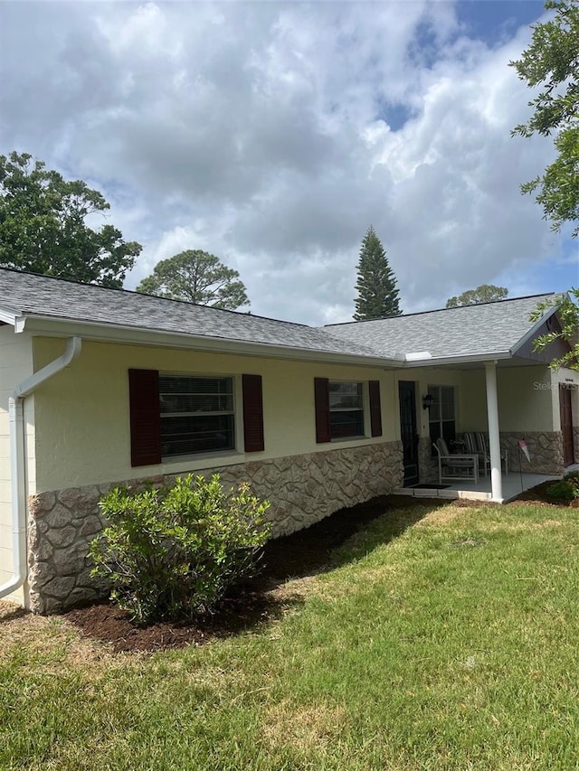 2408 Victory Palm Dr, Edgewater, FL 32141 - rear view of house with stone siding, a lawn, a shingled roof, and stucco siding