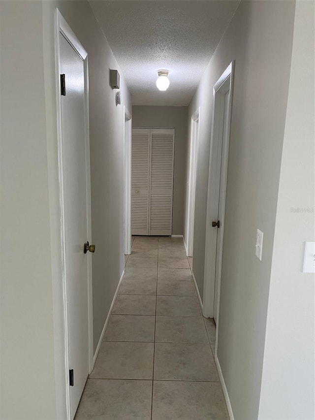2408 Victory Palm Dr, Edgewater, FL 32141 - corridor featuring a textured ceiling, light tile patterned flooring, and baseboards