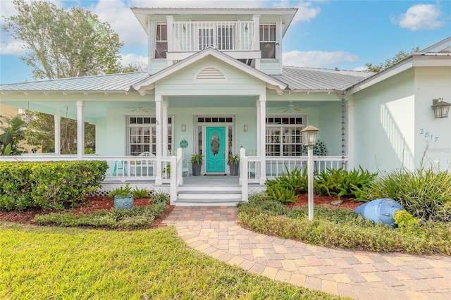 doorway to property featuring ceiling fan, a yard, and a porch