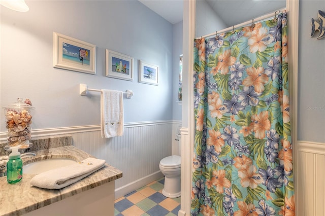 bathroom with toilet, vanity, and tile patterned flooring