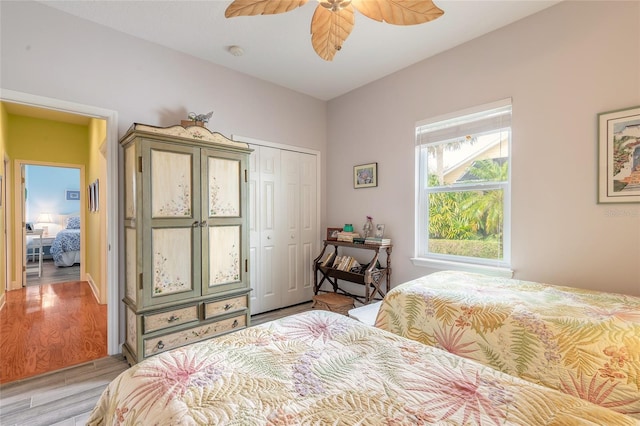 bedroom with light wood-type flooring, a closet, multiple windows, and ceiling fan