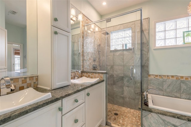 bathroom with a healthy amount of sunlight, separate shower and tub, and vanity