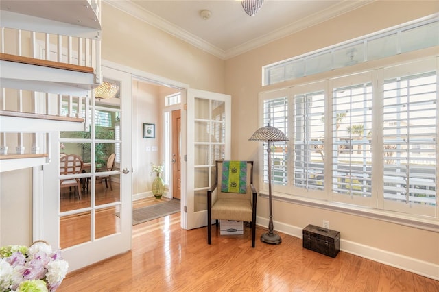 sitting room with light wood-type flooring, crown molding, and french doors