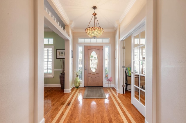 foyer featuring a healthy amount of sunlight, wood-type flooring, and ornamental molding