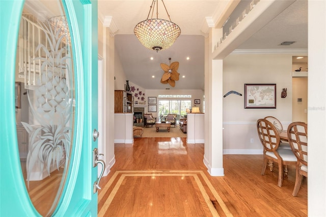 foyer with ceiling fan, crown molding, and light wood-type flooring