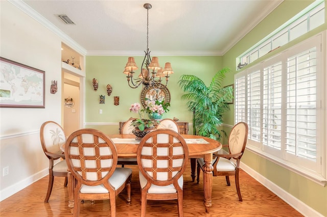 dining room featuring built in shelves, a notable chandelier, ornamental molding, and hardwood / wood-style floors