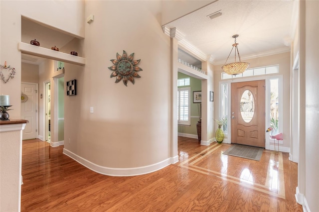 entrance foyer featuring wood-type flooring, ornamental molding, and a textured ceiling