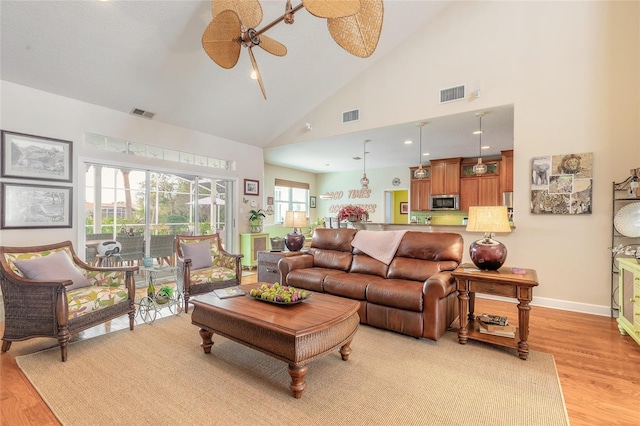 living room with light wood-type flooring, ceiling fan, and high vaulted ceiling