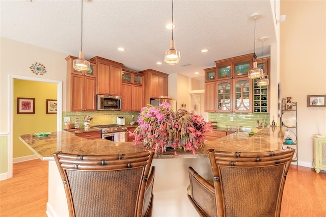 kitchen with decorative light fixtures, a breakfast bar, kitchen peninsula, and stainless steel appliances