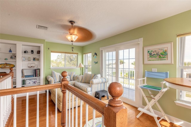 living room featuring a textured ceiling, ceiling fan, and light hardwood / wood-style floors