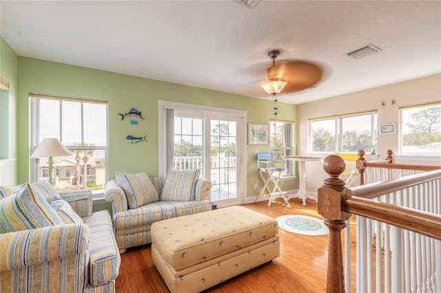 living room featuring hardwood / wood-style flooring, a textured ceiling, and ceiling fan