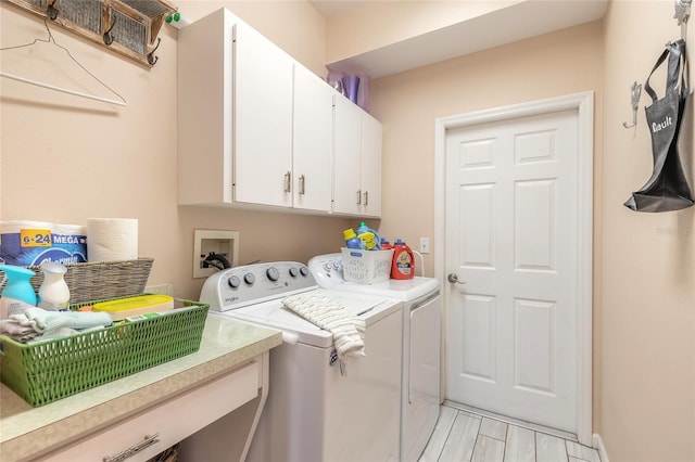 clothes washing area featuring cabinets and washer and clothes dryer