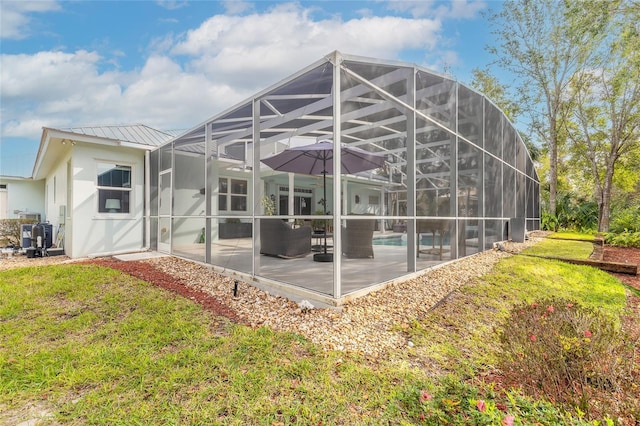 back of house featuring glass enclosure, a patio area, and a yard