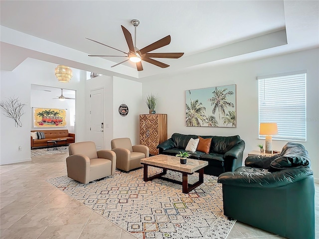 tiled living room with a raised ceiling and a ceiling fan