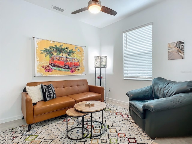 living area featuring a ceiling fan, visible vents, and baseboards