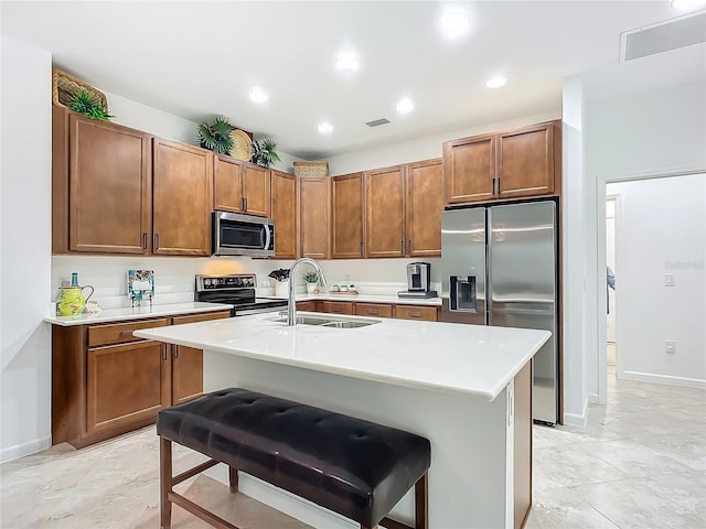 kitchen featuring brown cabinets, stainless steel appliances, visible vents, a sink, and a kitchen bar