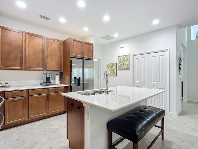 kitchen with brown cabinets, visible vents, a sink, and stainless steel fridge with ice dispenser