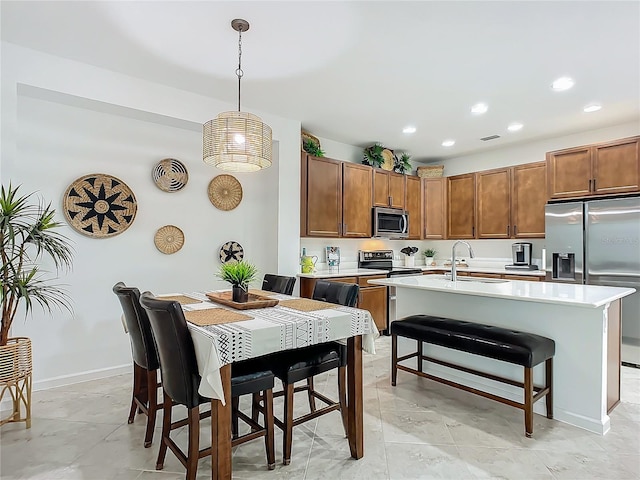 kitchen featuring light countertops, appliances with stainless steel finishes, a sink, and brown cabinets