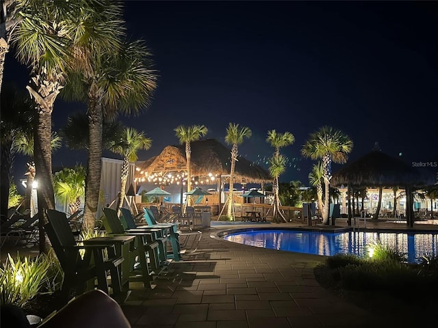 pool at night featuring a community pool and a patio