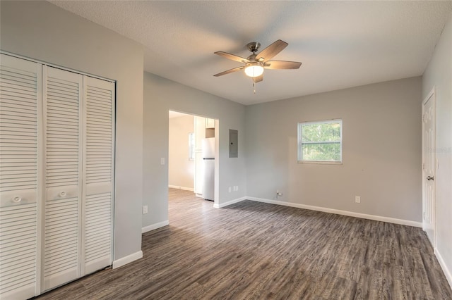 unfurnished bedroom featuring a textured ceiling, dark hardwood / wood-style flooring, white refrigerator, a closet, and ceiling fan