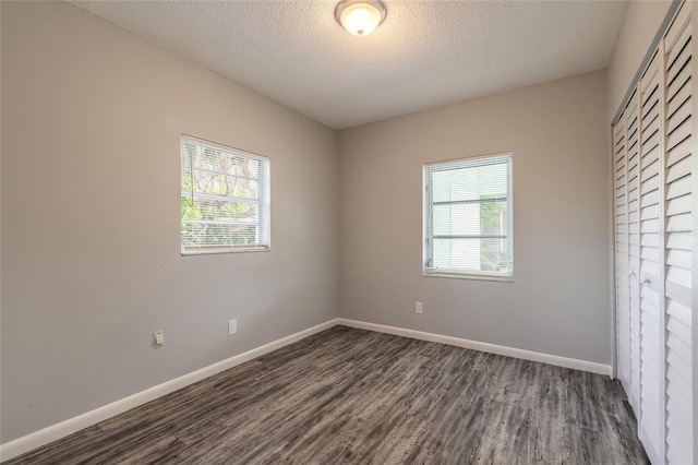 spare room featuring dark wood-type flooring and a textured ceiling