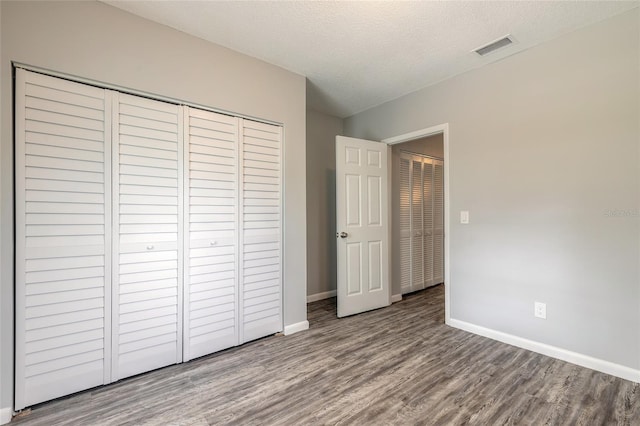 unfurnished bedroom featuring a textured ceiling, a closet, and hardwood / wood-style floors